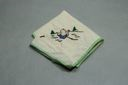 Image of Figure sitting with back turned, one of a set of 4 embroidered napkins, each with figure at play